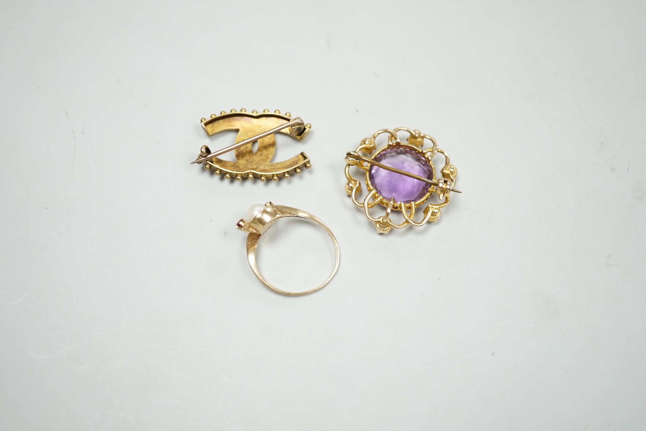An Edwardian yellow metal and split pearl set double horseshoe brooch, 26mm, an amethyst and split pearl set yellow metal brooch and a modern 9ct god and gem set ring, gross weight 11.8 grams.
